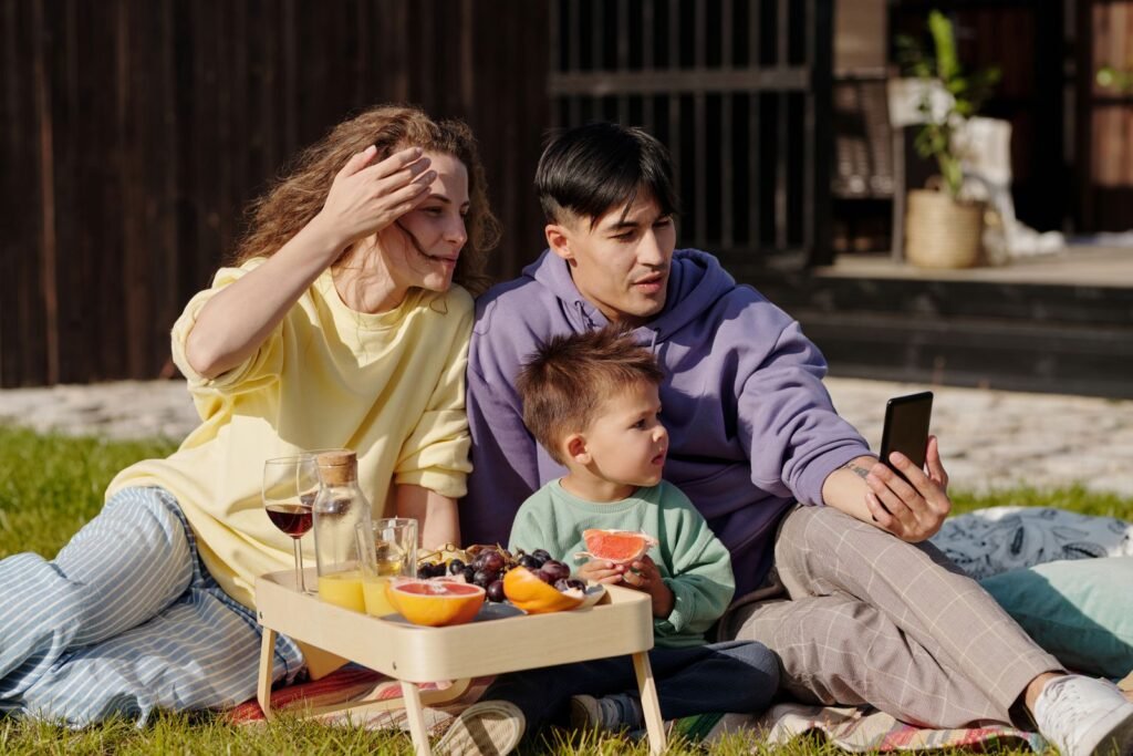 Famille assise dans l herbe qui consulte un smartphone, vérifier l affluence à Plopsaland De Panne