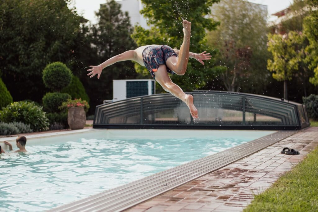 Garçon qui saute dans une piscine de jardin, idée d Airbnb avec piscine près de Plopsaland
