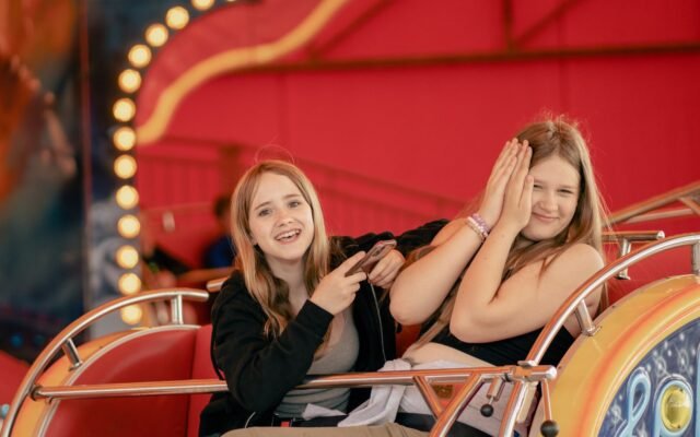 Deux amies souriantes dans un manège, qui profitent du parc grâce à un coupe-file Speedy pour Kondaa
