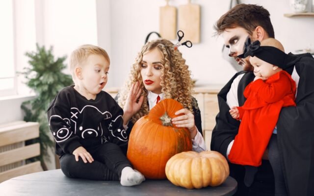 Famille déguisée qui décore des citrouilles, Halloween en famille à Plopsaland De Panne