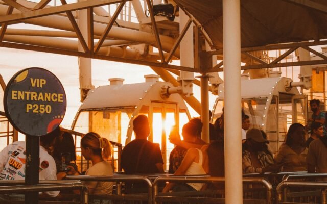 Visiteurs devant une grande roue au coucher du soleil, à la recherche de l'heure idéale pour faire le Kondaa
