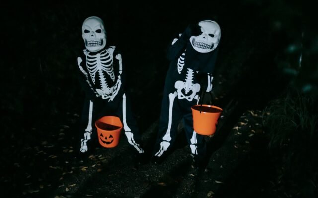 Deux enfants déguisés en squelettes avec des seaux citrouille la nuit, nocturne Halloween à Plopsaland