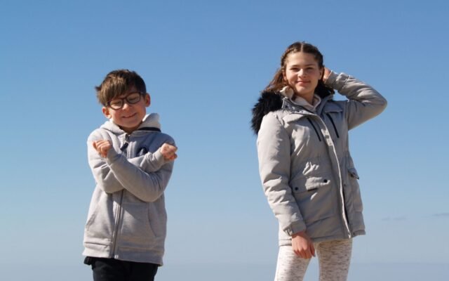 Deux enfants en manteau sur la plage de la mer du Nord, vacances scolaires en Belgique et Plopsaland