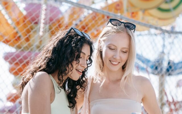 Deux amies consultent leur smartphone dans un parc d'attractions pour vérifier le temps d'attente de Kondaa