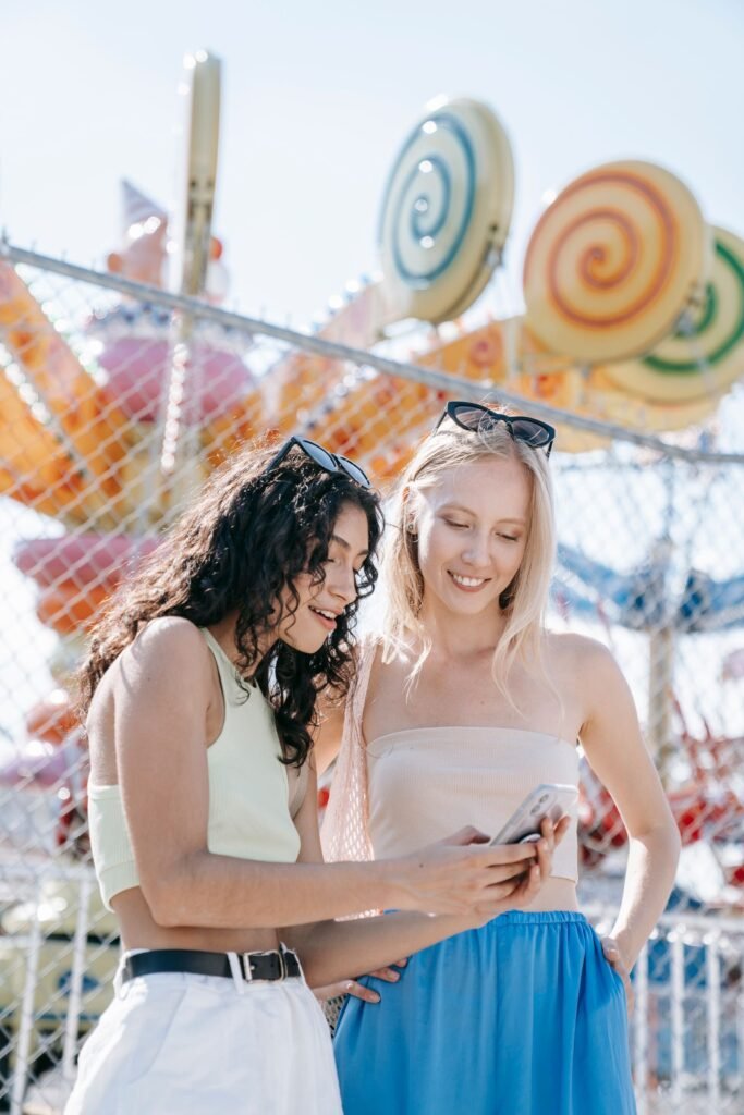 Deux amies consultent leur smartphone dans un parc d'attractions pour vérifier le temps d'attente de Kondaa